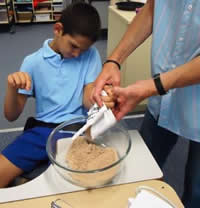 Teacher helping a student make a cake