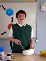 Student smiling while baking a cake